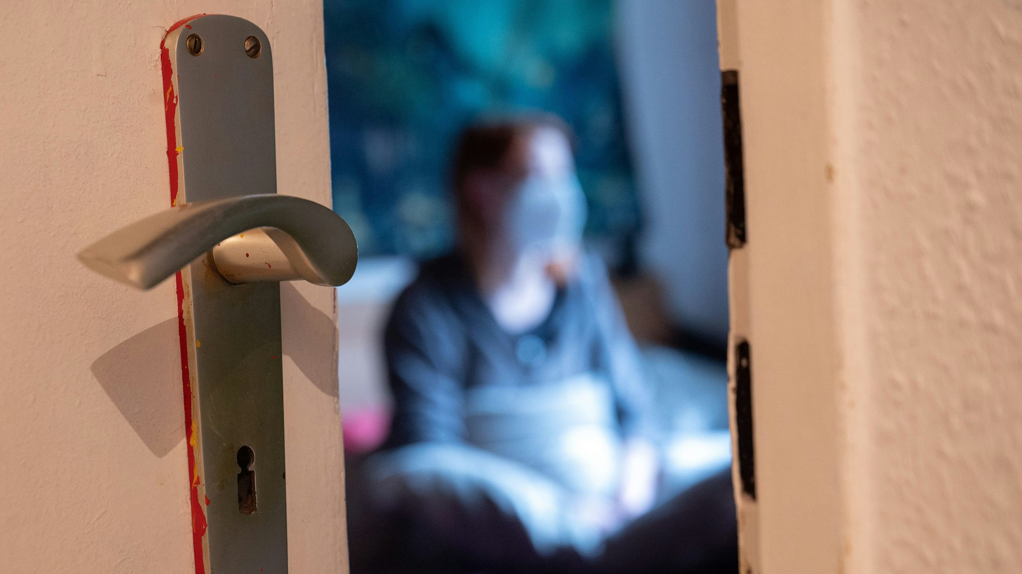 Eine Frau sitzt während der Isolation nach einem positiven Corona-PCR-Test auf ihrem Bett.