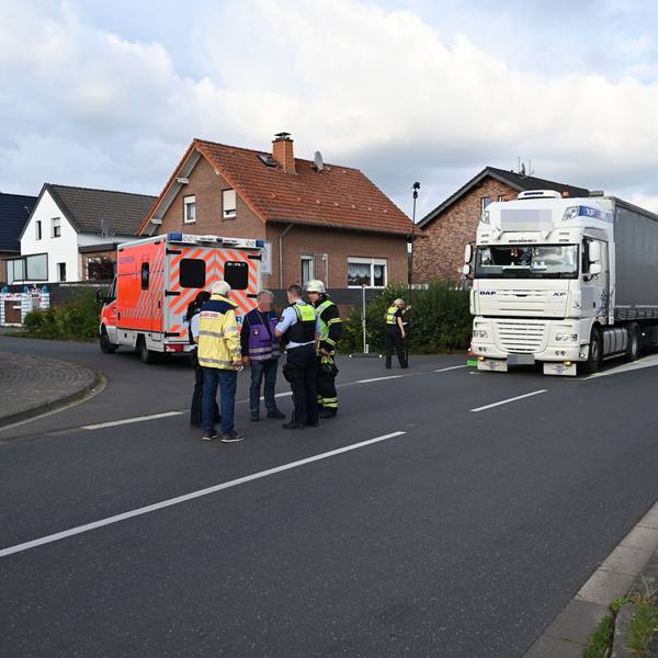 Ein Lkw steht auf der Straße, ein Rettungswagen daneben. Ein paar Menschen stehen davor.