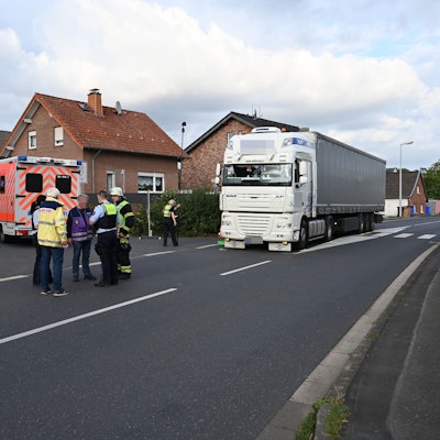 Ein Lkw steht auf der Straße, ein Rettungswagen daneben. Ein paar Menschen stehen davor.