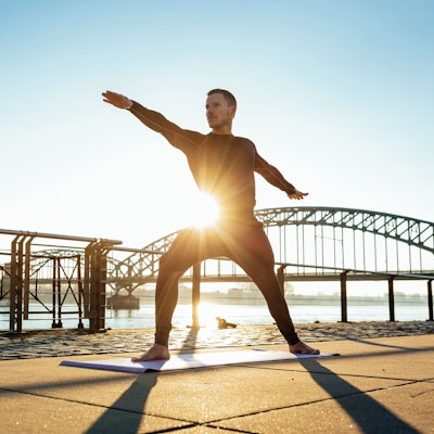 Ein Mann in Yoga-Position am Rheinufer in Köln.