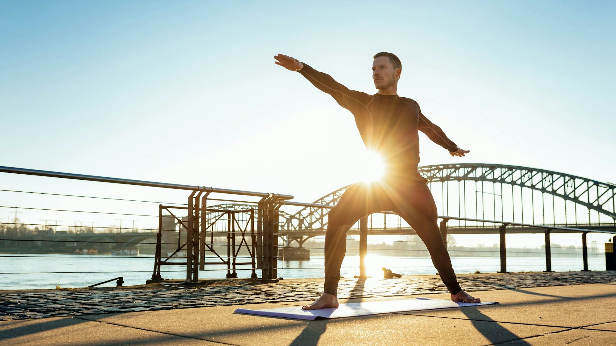 Ein Mann in Yoga-Position am Rheinufer in Köln.