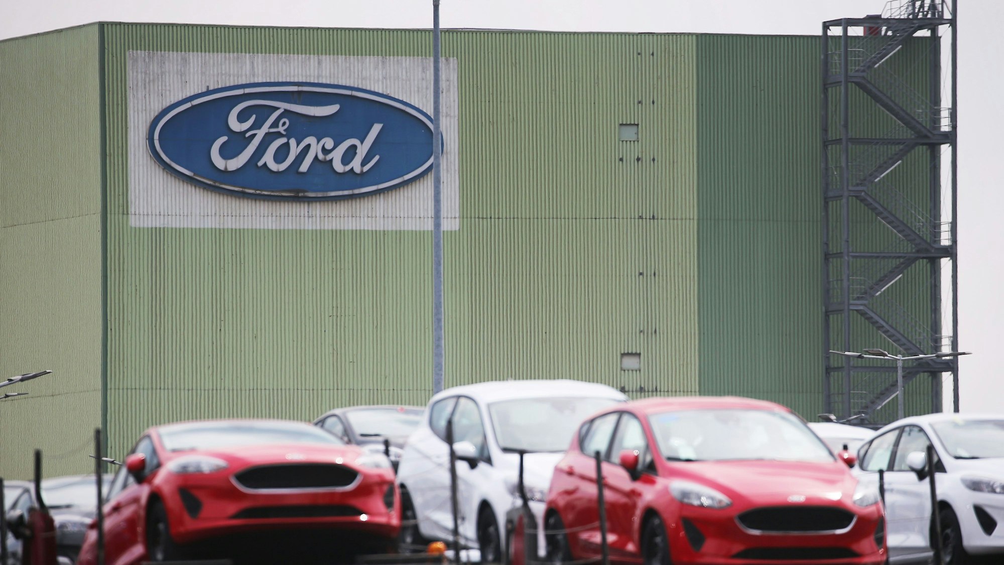 Neu gebaute Autos stehen auf Lastwagen vor dem Ford Werk in Köln.