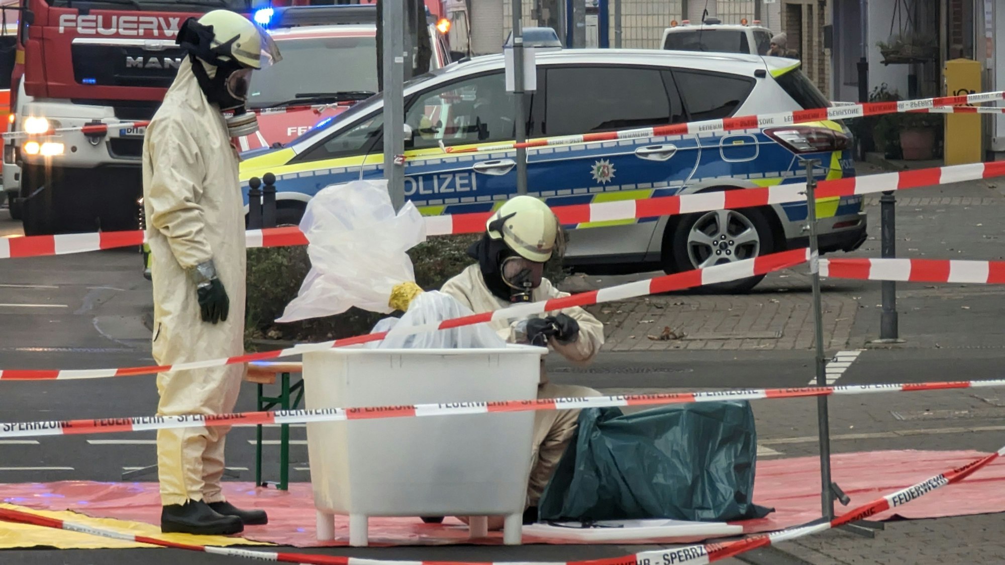 Zwei Einsatzkräfte begutachten die Substanz in Schutzanzügen in einem abgesperrten Bereich.