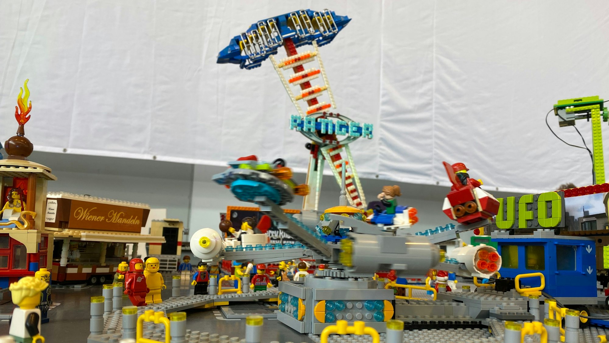 Aus vielen bunten Klemmbausteinen ist eine Kirmes mit verschiedenen Elementen aufgebaut.