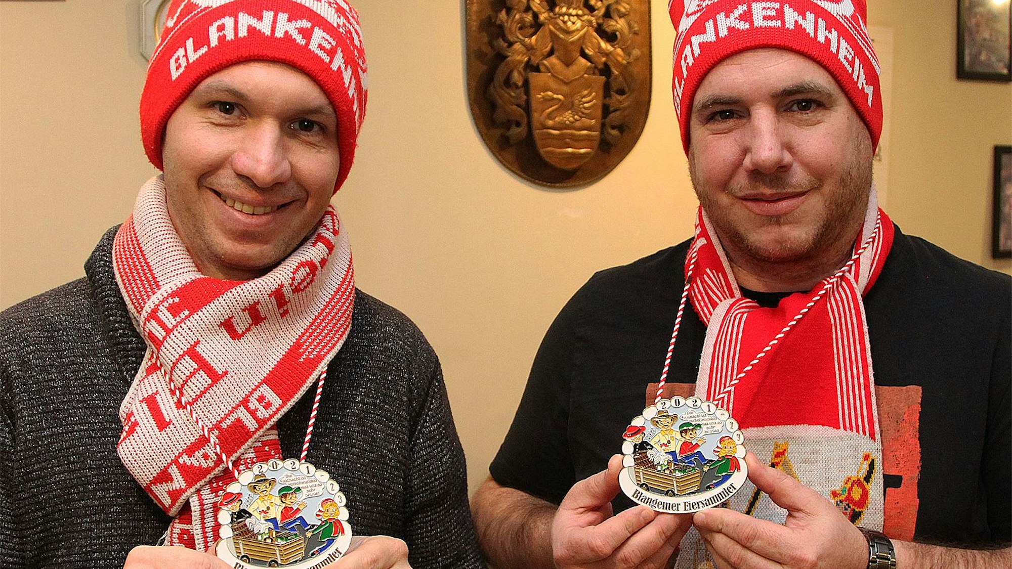 Zwei Karnevalisten sind mit Schal und Mütze ausgestattet und präsentieren den Orden.