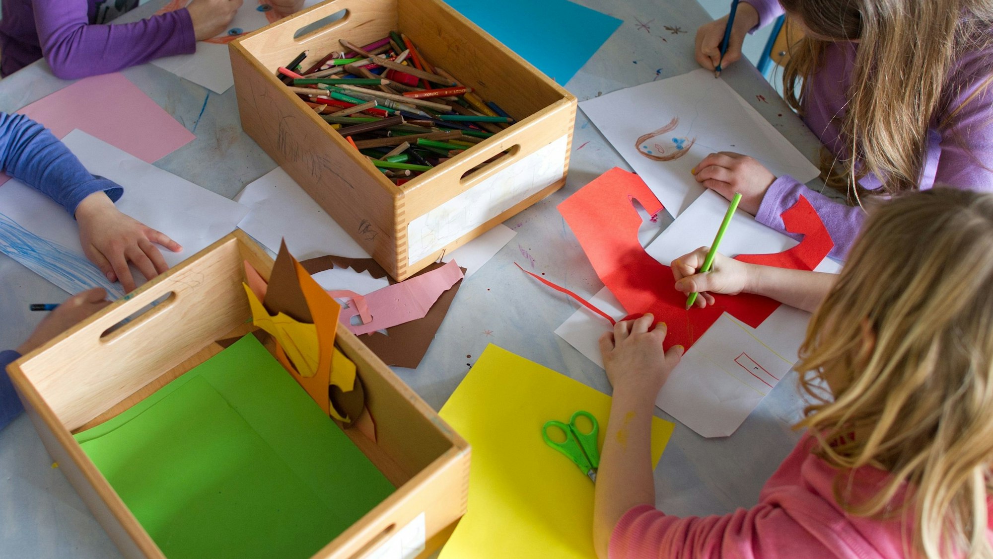 Grundschülerinnen sind in einem Kinderhort mit Bastelarbeiten beschäftigt.