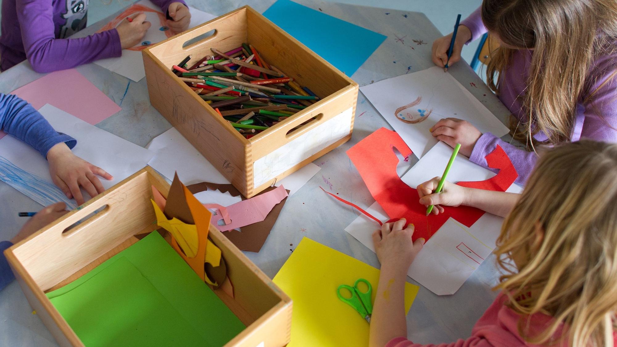 Grundschülerinnen sind in einem Kinderhort mit Bastelarbeiten beschäftigt.
