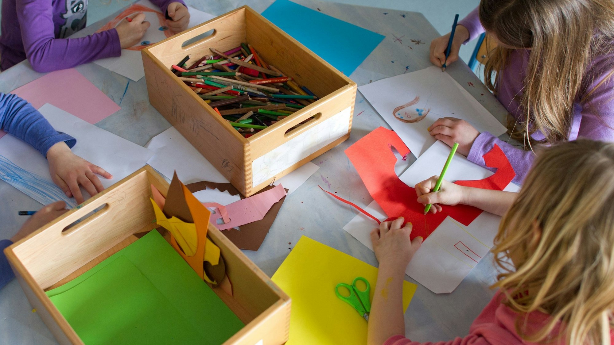 Grundschülerinnen sind in einem Kinderhort mit Bastelarbeiten beschäftigt.