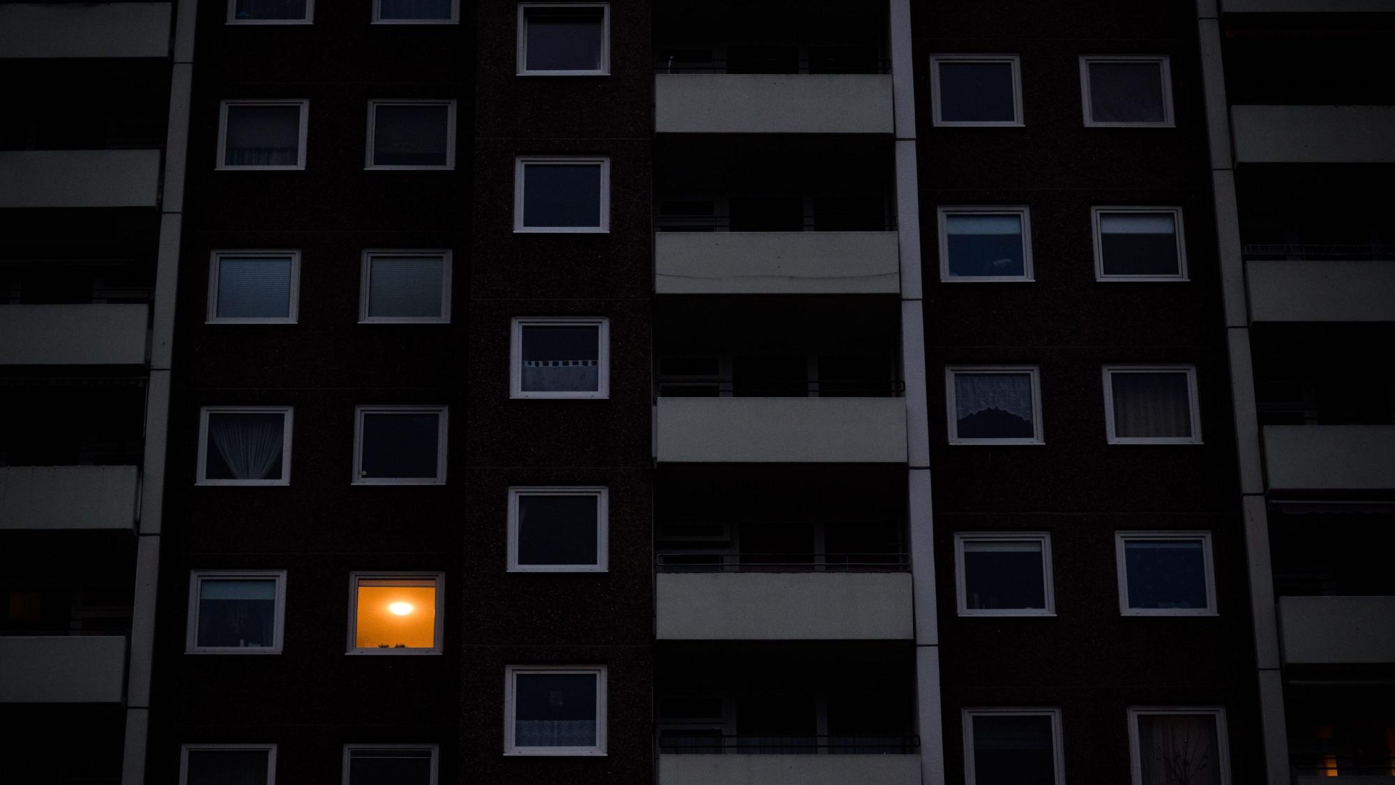 Nur in einer Wohnung eines Mehrfamilienhauses brennt am frühen Morgen Licht. Die teils massiv gestiegenen Preise für Gas und Strom bereiten viele Menschen in Deutschland finanzielle Schwierigkeiten.