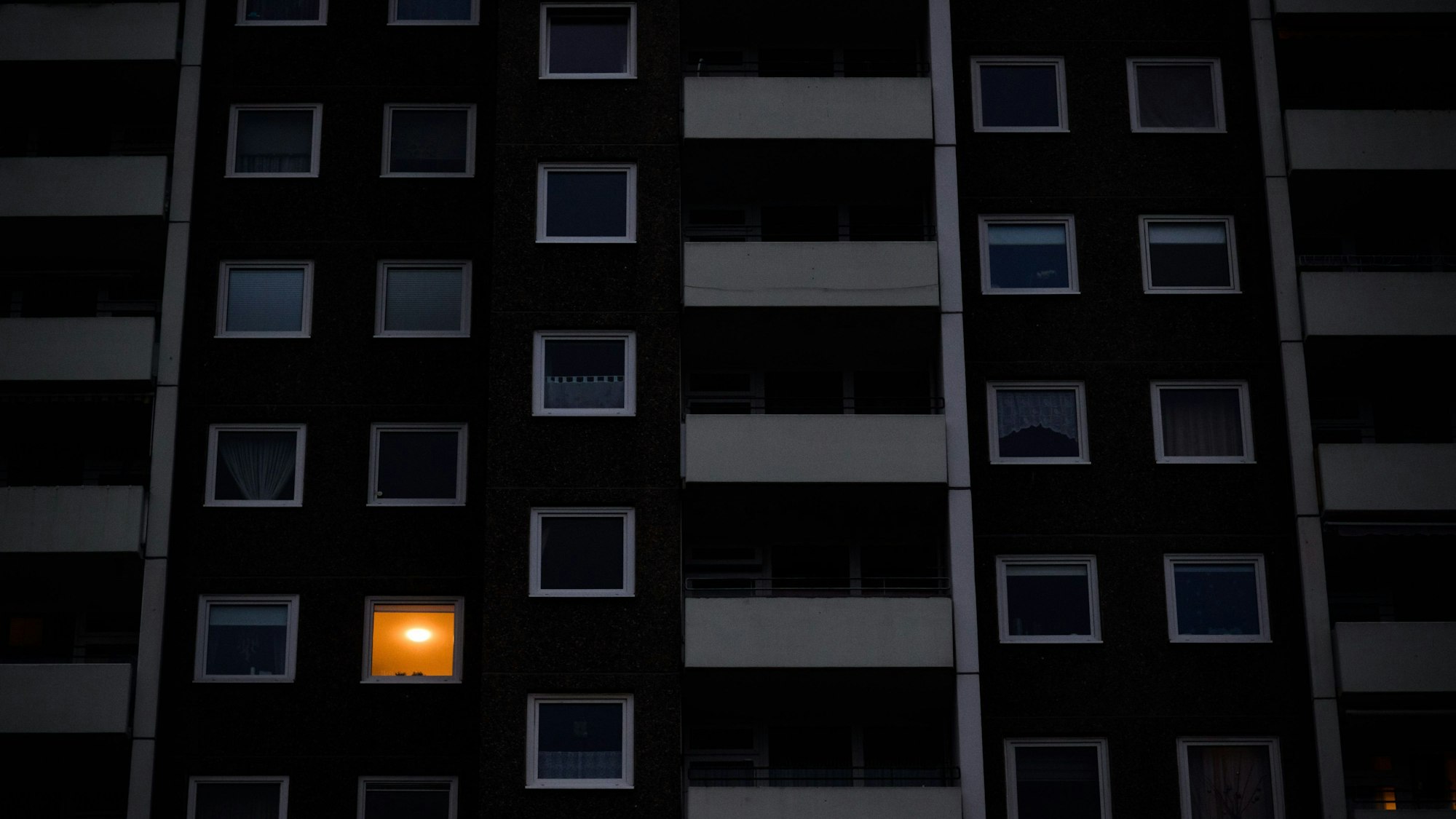 Nur in einer Wohnung eines Mehrfamilienhauses brennt am frühen Morgen Licht. Die teils massiv gestiegenen Preise für Gas und Strom bereiten viele Menschen in Deutschland finanzielle Schwierigkeiten.