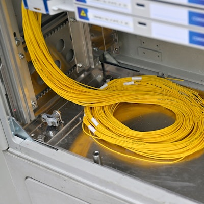 Ein Bündel gelber Glasfaserkabel liegt in einem Verteilerkasten.