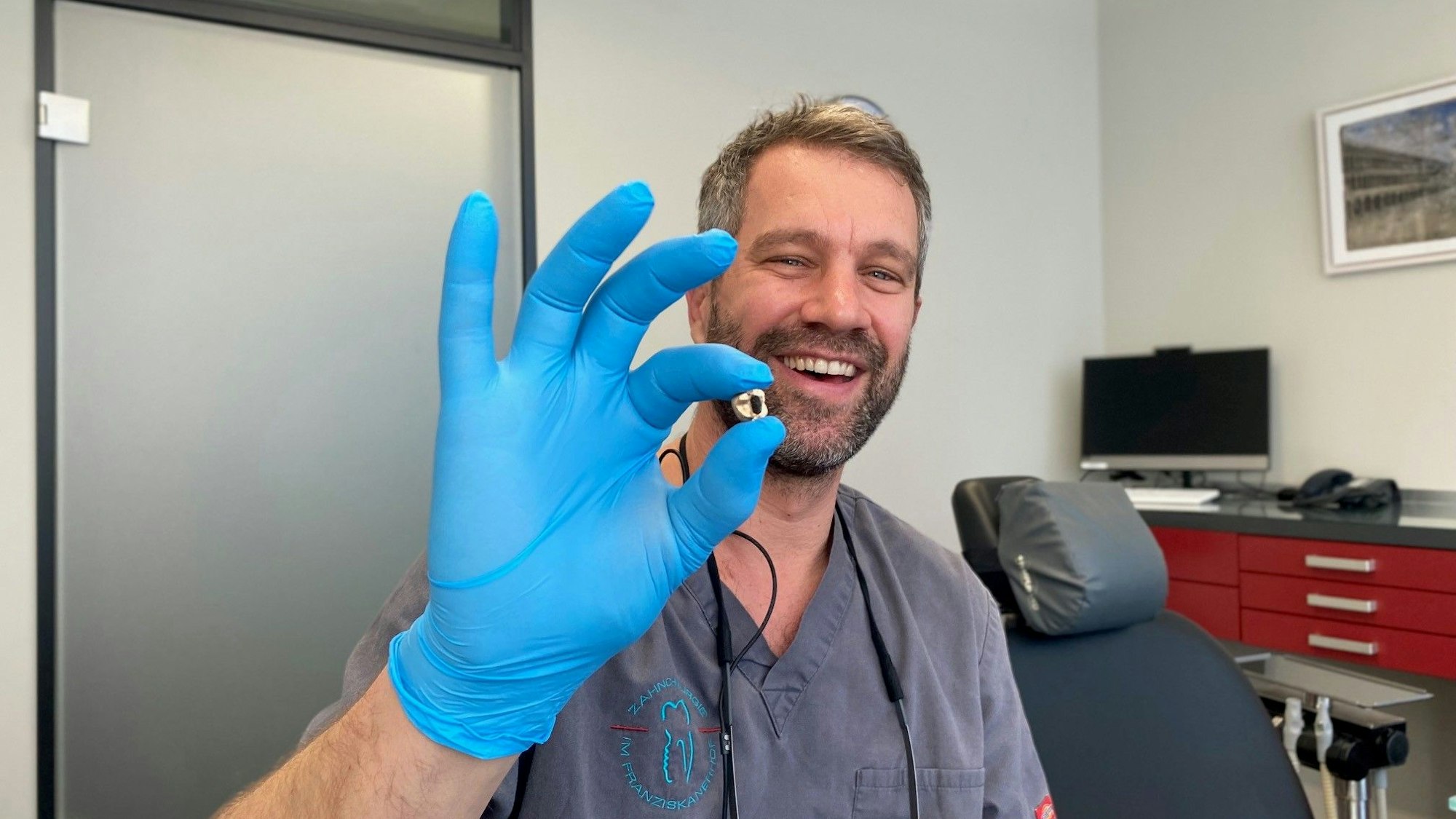 Zahnarzt Benjamin Engelke mit entnommenen Zahngold in der Hand.