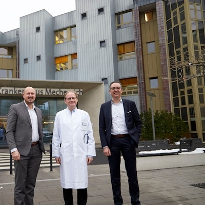 Drei Männer, der Mittlere im Arztkittel, stehen vor dem Eingang zum Kreiskrankenhaus Mechernich.