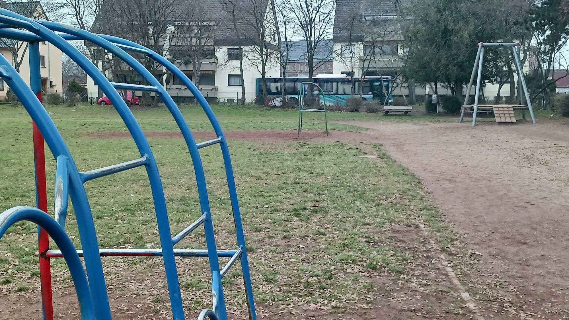 Spielgeräte stehen auf einer verdorrten Wiese.