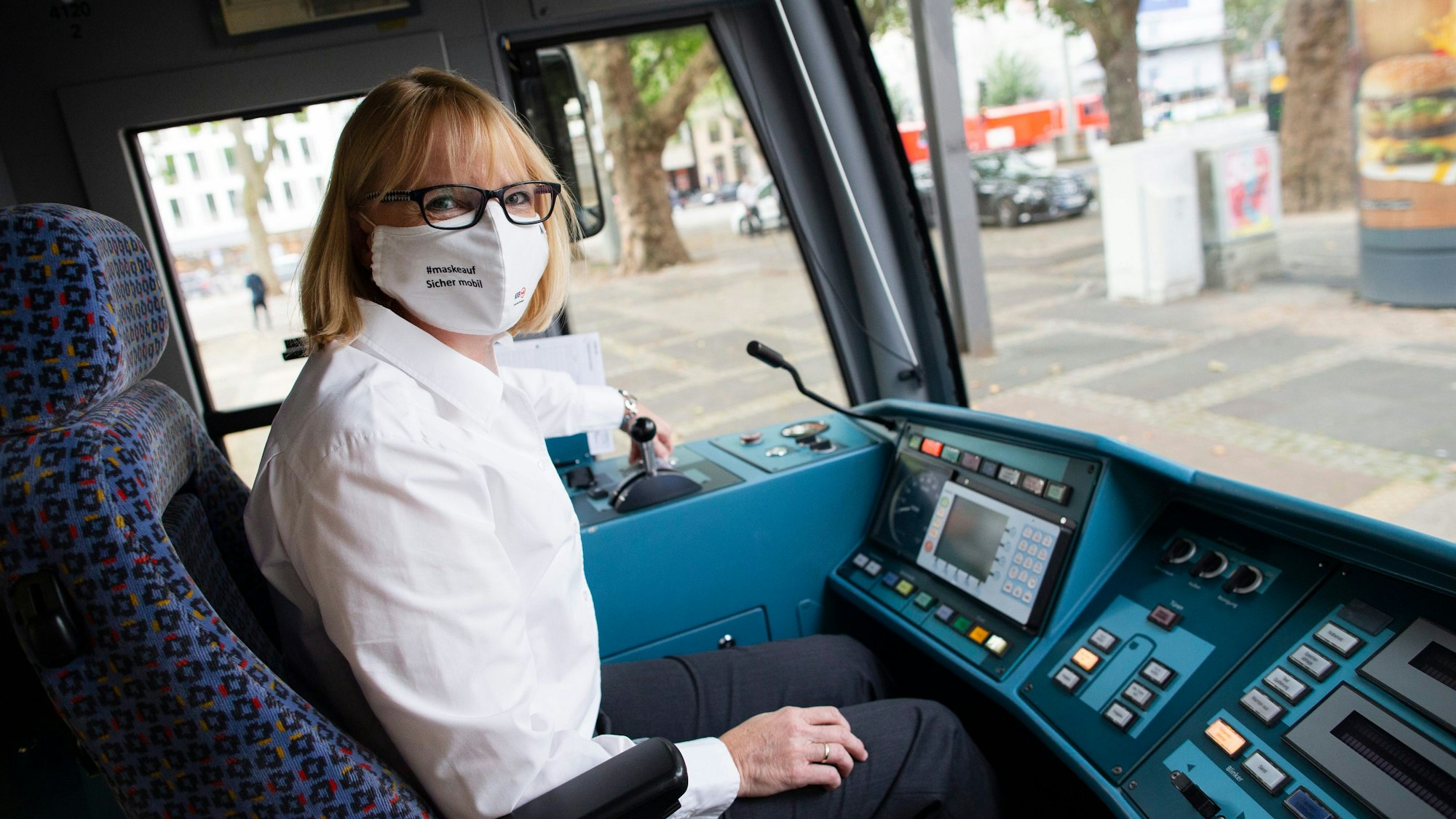 Stefanie Haaks, Chefin der Kölner Verkehrs-Betriebe sitzt mit Mund-Nase-Schutz am Steuer einer Kölner Stadtbahn.