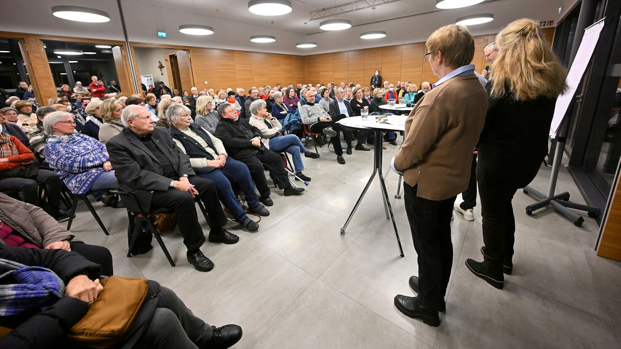 Menchen sitzen in einem gut gefällten Gemeindesaal in Refrath.