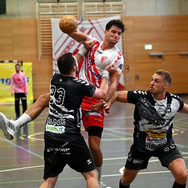 Ein Handballer wird beim Wurfversuch von seinem Gegenspieler am Trikot gehalten.