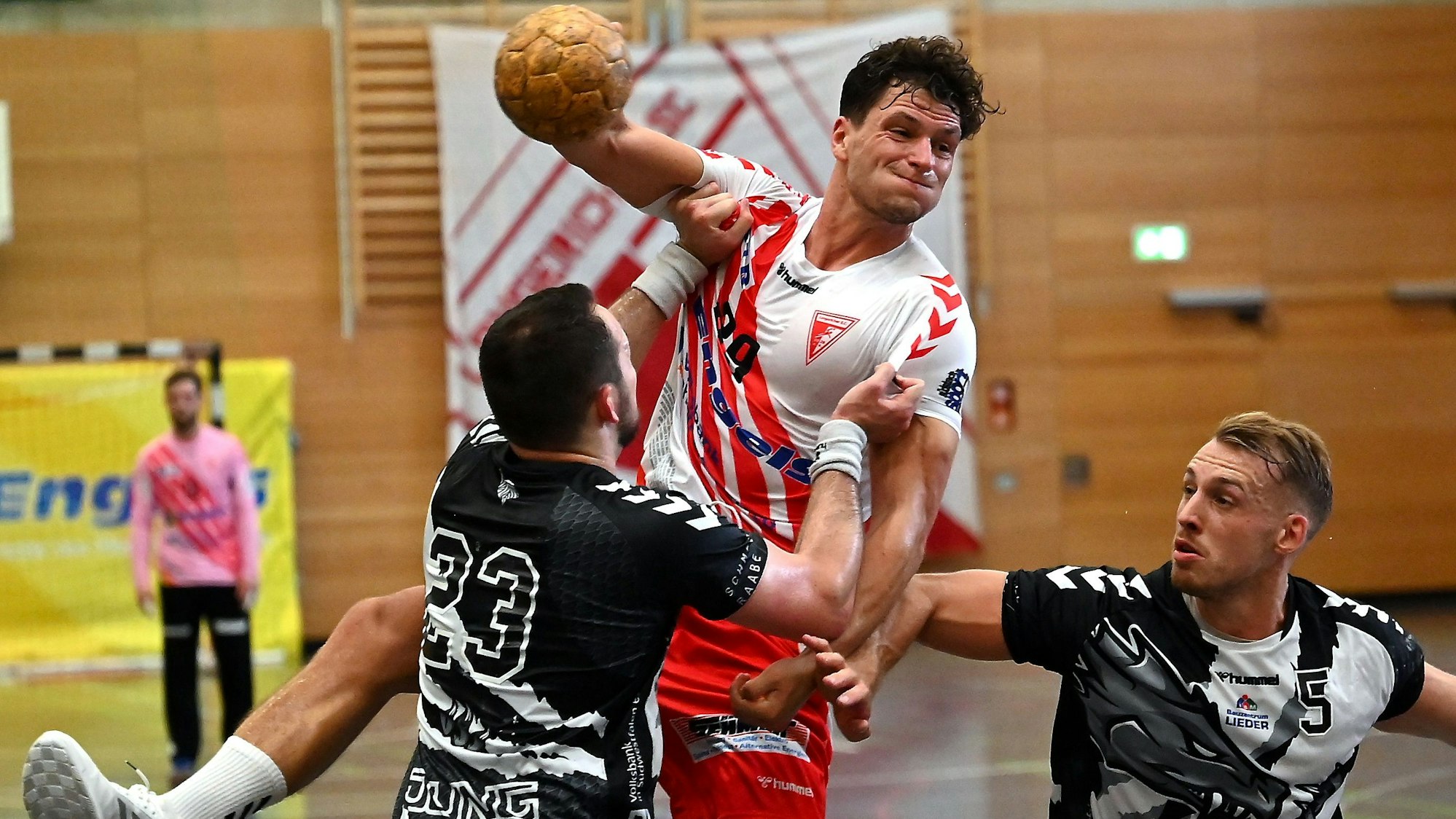 Ein Handballer wird beim Wurfversuch von seinem Gegenspieler am Trikot gehalten.