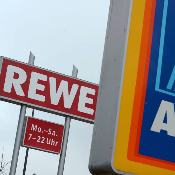 Schilder des Discounters Aldi Süd und der Supermarktkette Rewe stehen an der Zufahrt eines Industriegebiets in Glashütten (Hessen).