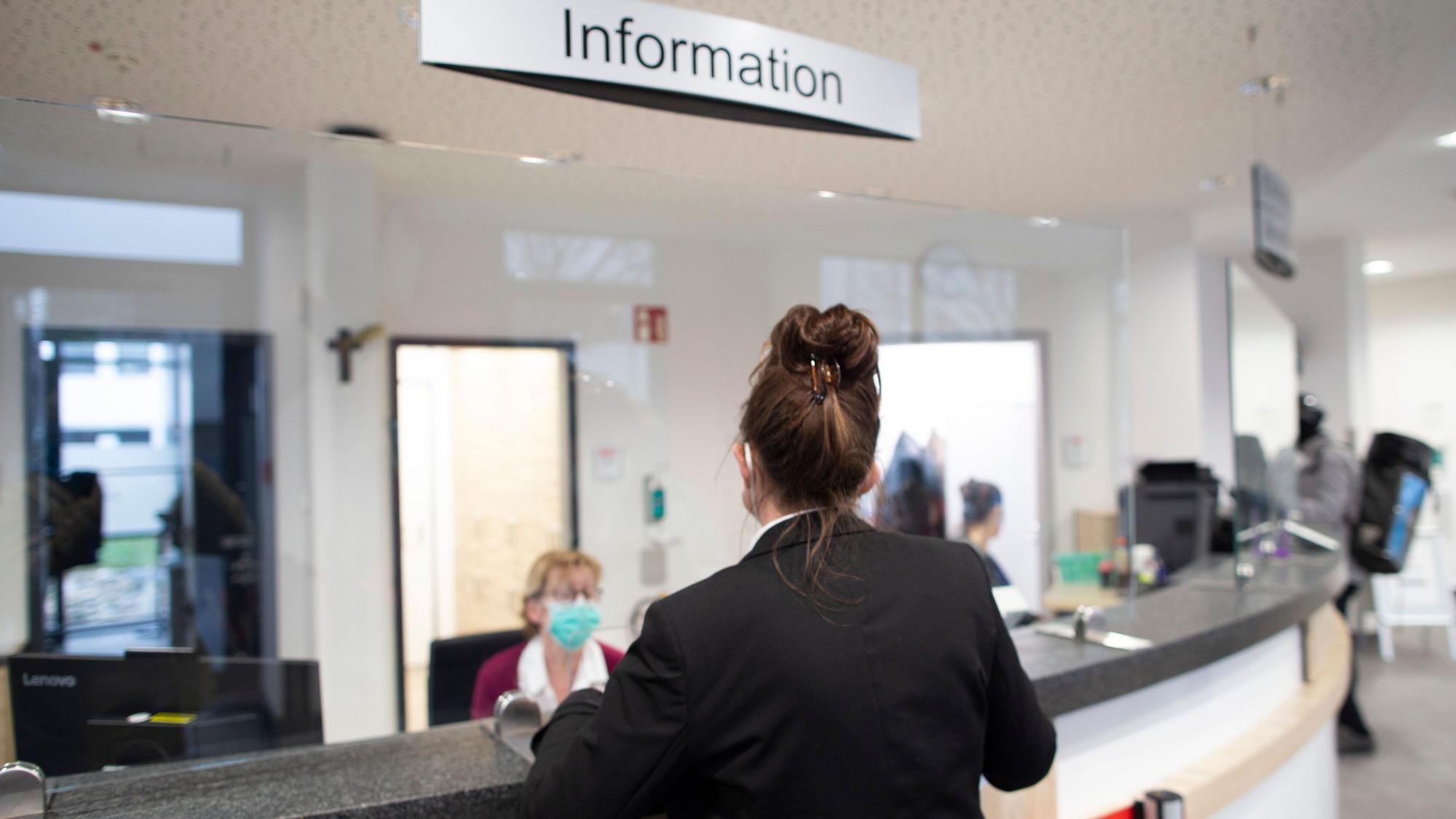 Eine Frau steht an der Anmeldung eines Krankenhauses.