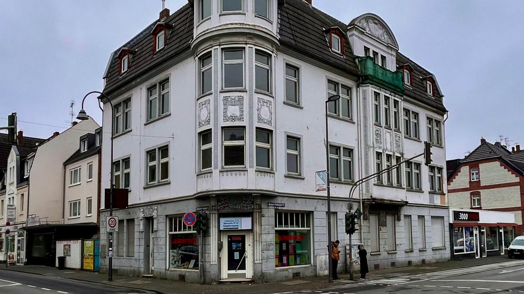Ein vierstöckige Altbau an einer Straßenecke mit weißer Fassade ist zu sehen.