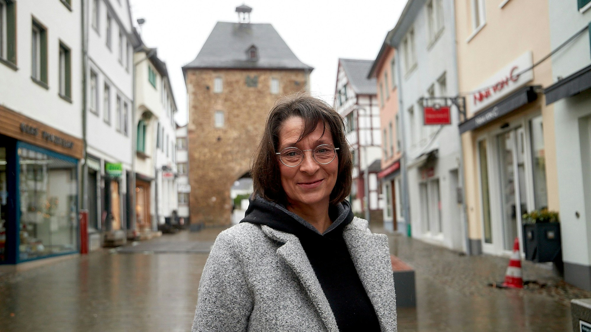 Eine Frau steht auf einer Straße in Bad Münstereifel, im Hintergrund ist das Orchheimer Tor zu sehen.
