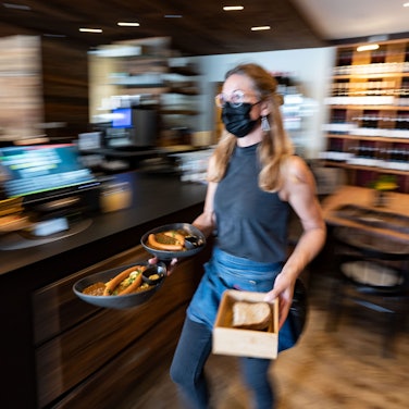 Eine Kellnerin trägt in einem Restaurant Essensteller