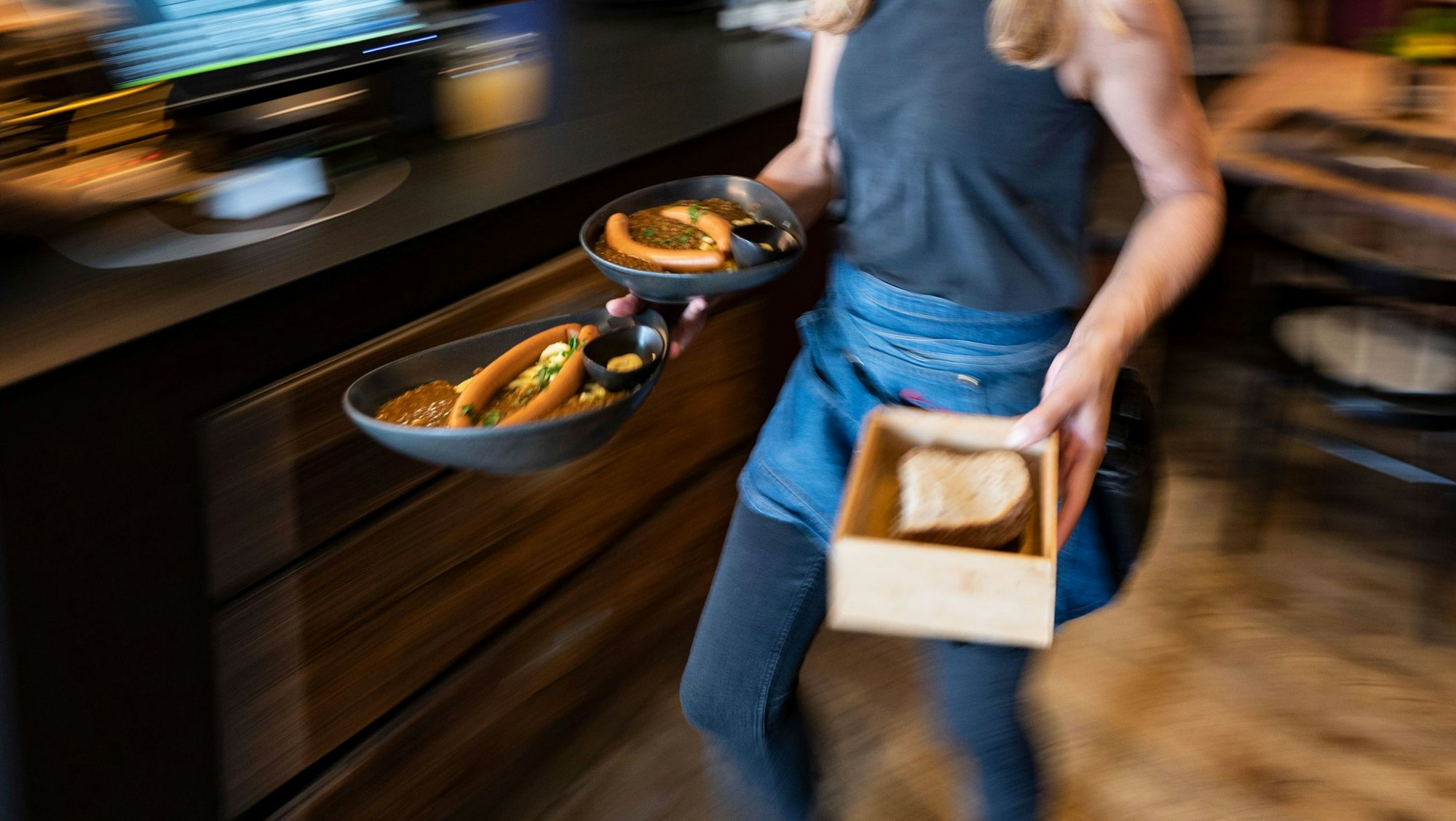 Eine Kellnerin trägt in einem Restaurant Essensteller