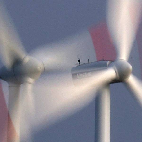 Zwei Windräder drehen sich bei heftigem Wind vor bewölkten Himmel.