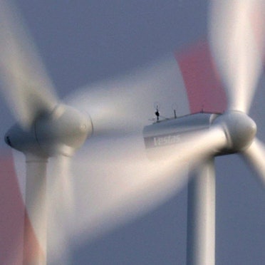 Zwei Windräder drehen sich bei heftigem Wind vor bewölkten Himmel.