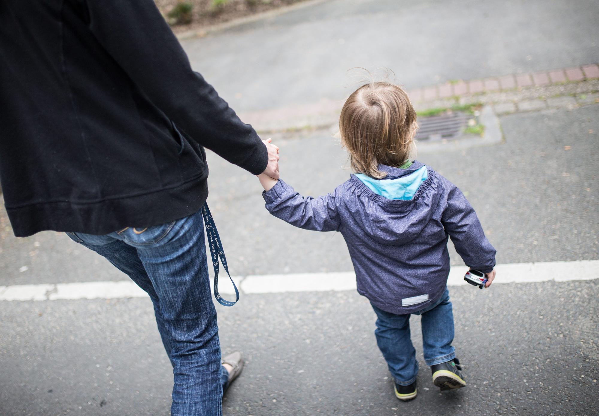 Eine Mutter hält ihren Sohn an der Hand.