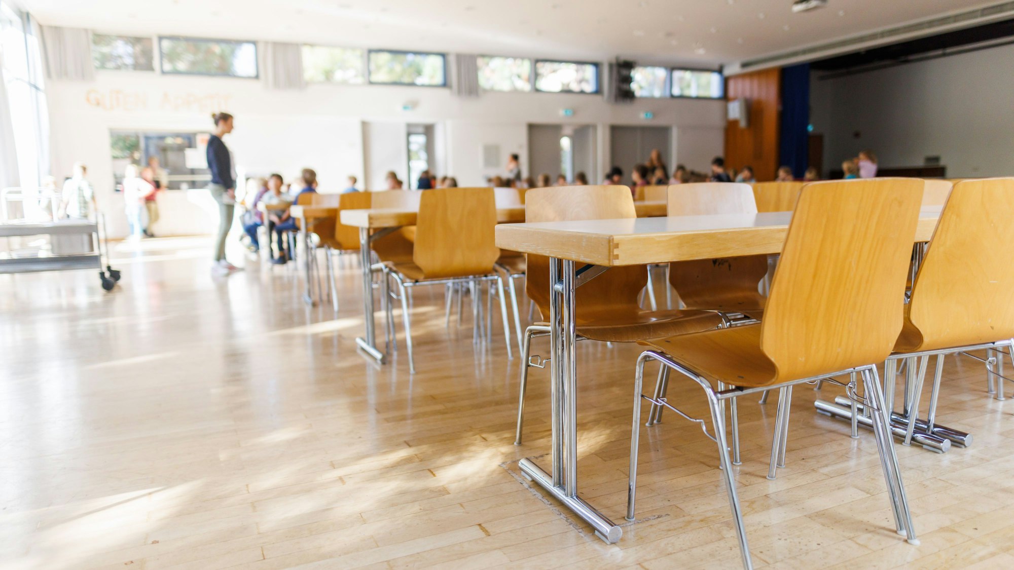 Stühle und Tische für Erwachsene stehen in einer zur Schulmensa.