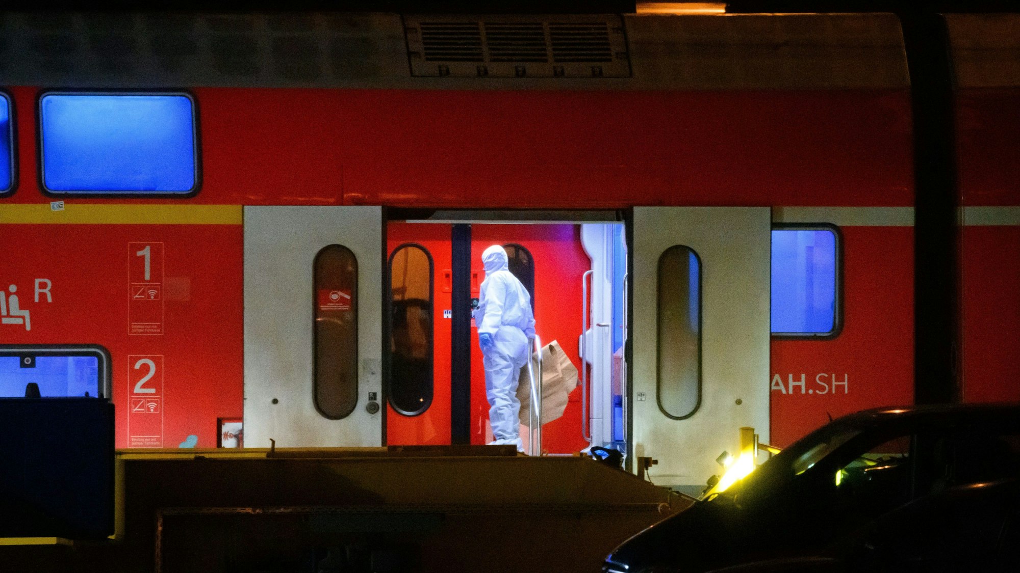 Ein Ermittler im weißen Schutzanzug arbeitet in dem Regionalzug, der auf ein Abstellgleis in Neumünster gefahren worden war.