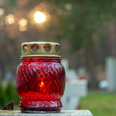 Eine Kerze steht auf einem Grab.