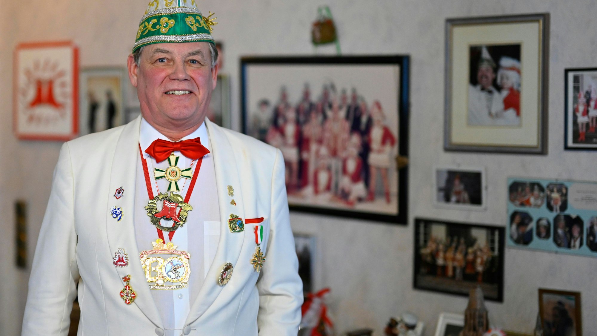 Armin Gries steht vor einer Wand mit vielen Fotos aus seiner Karnevalszeit.
