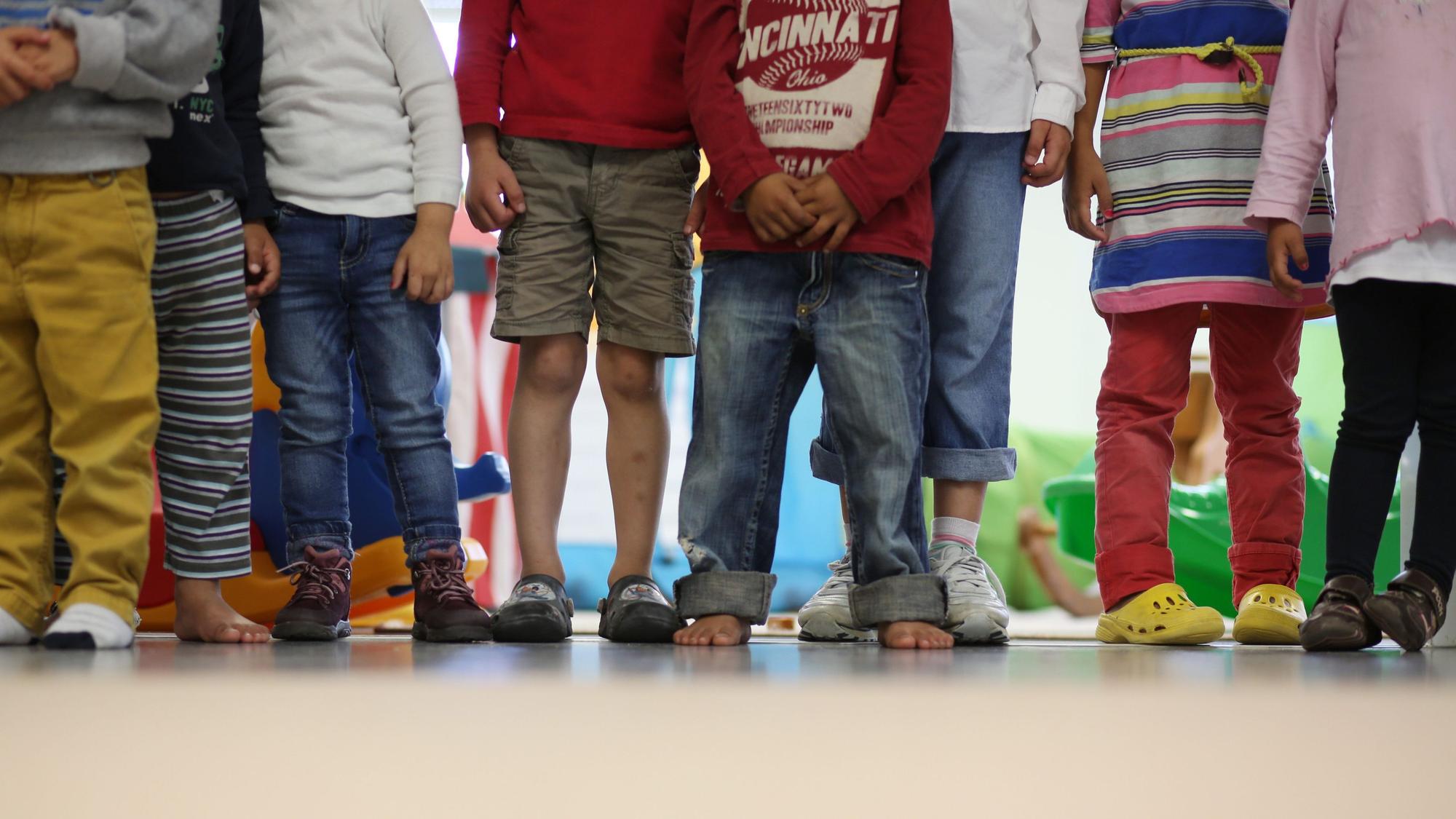 Kinder stehen in einem Raum, es sind nur die Beine zu sehen.