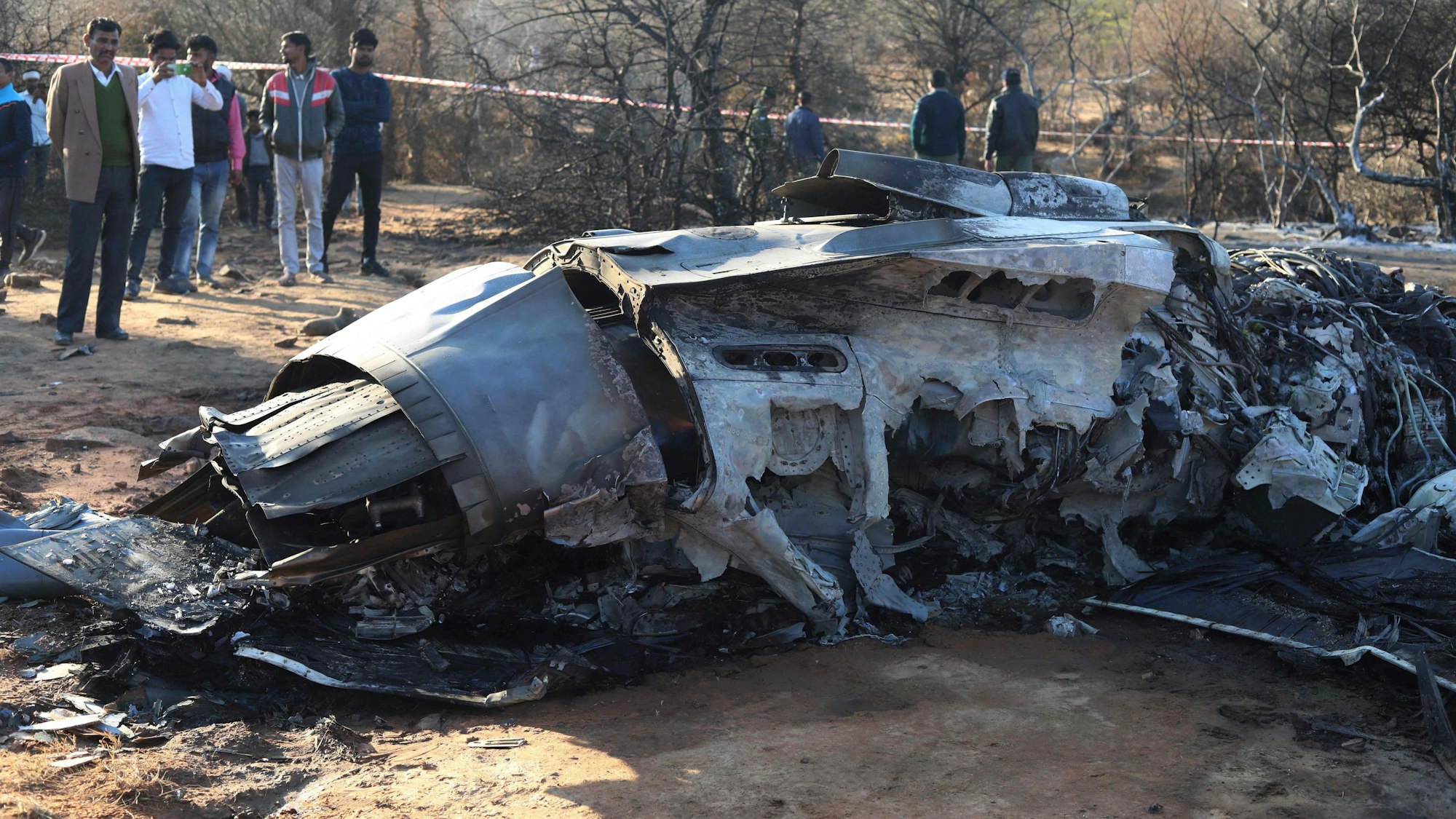Menschen stehen neben einem dem Wrack einer russischen Sukhoi Su-30, bei einer Routineübung in Indien kam es zur Kollision von zwei Jets.