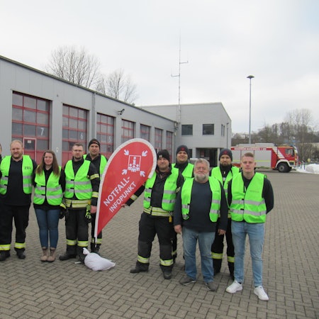Eine Gruppe von Feuerwehrleuten steht vor ihrer Wache.