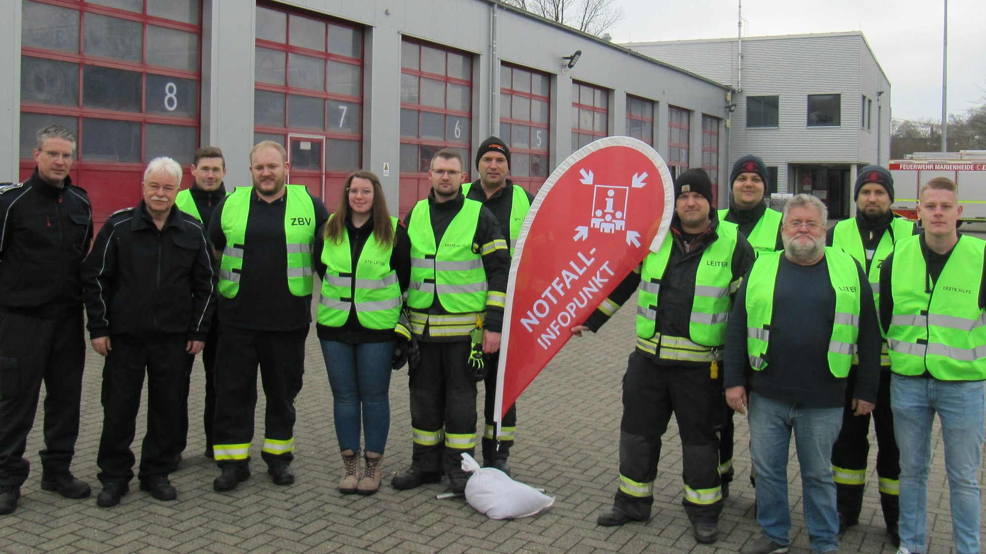 Eine Gruppe von Feuerwehrleuten steht vor ihrer Wache.