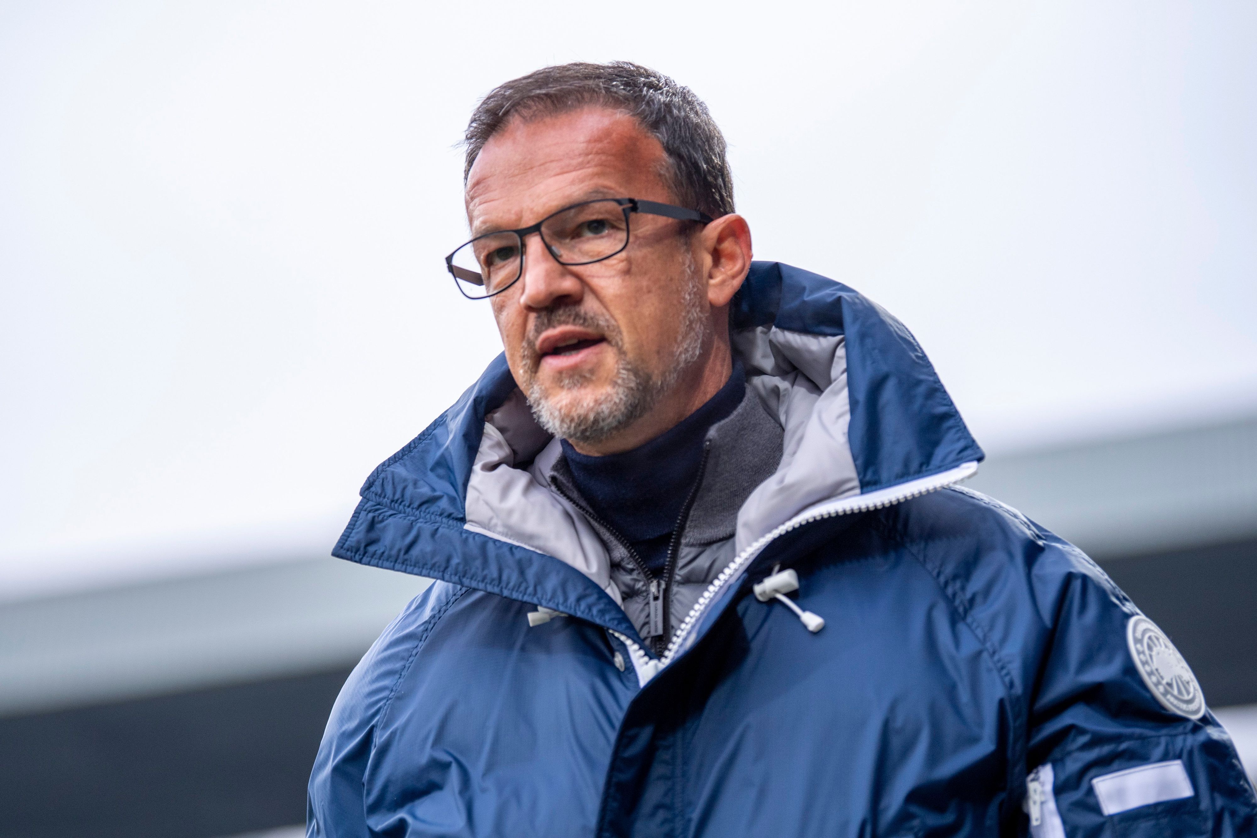 Fredi Bobic steht in einer dicken Jacke in einem Stadion.