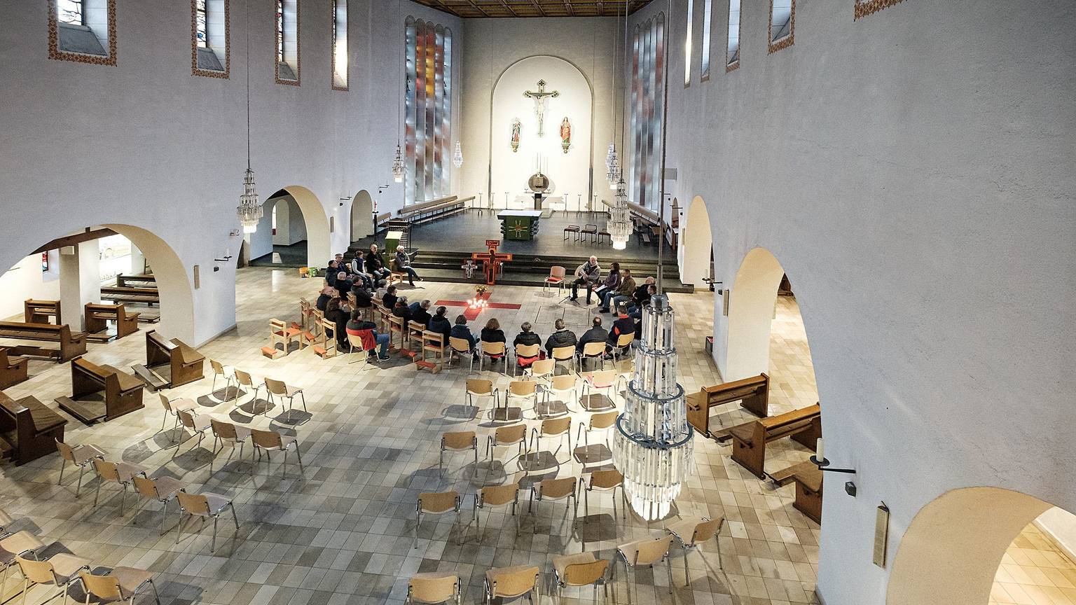 In der Kirche St Martin in Rheinbach wurden die alten Bänke weggeräumt. Eine Gruppe sitzt zur Andacht im Kreis beisammen.