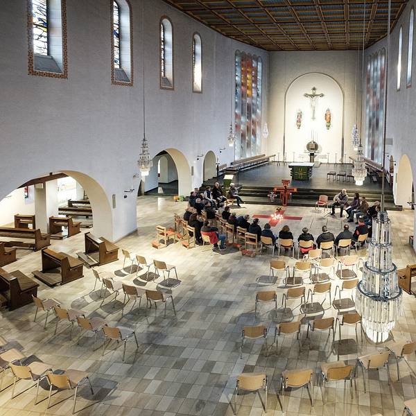 In der Kirche St Martin in Rheinbach wurden die alten Bänke weggeräumt. Eine Gruppe sitzt zur Andacht im Kreis beisammen.