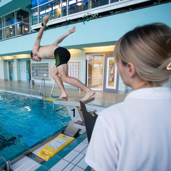 Ein junger Mann springt von einem Startblock im Aggripabad in Köln.
