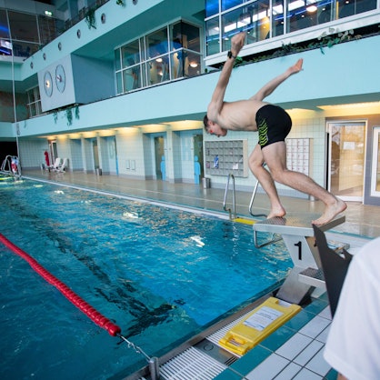 Ein junger Mann springt von einem Startblock im Aggripabad in Köln.