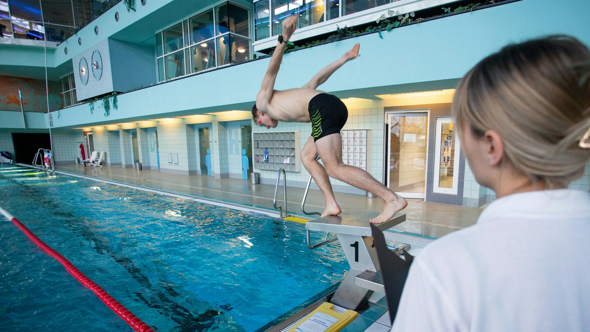 Ein junger Mann springt von einem Startblock im Aggripabad in Köln.
