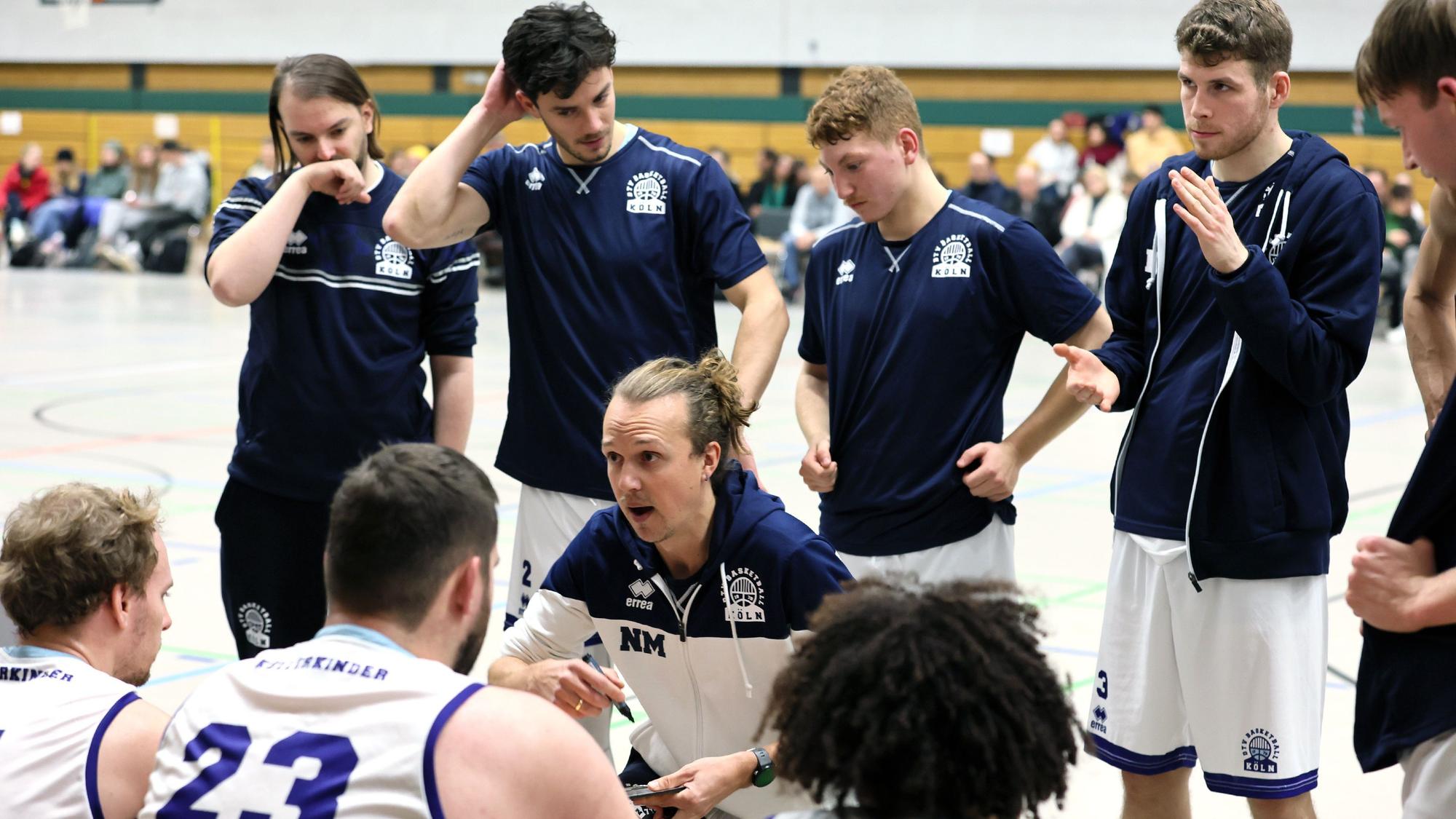 Ein Basketballtrainer bespricht sich mit seinem Team in einer Auszeit.