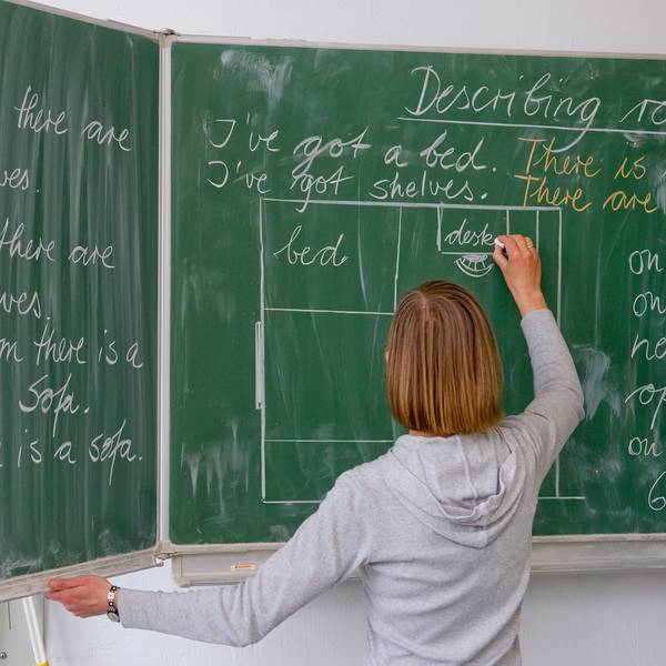 Eine Englisch-Lehrerin einer Grundschule schreibt Unterrichtsinhalte an die Tafel.