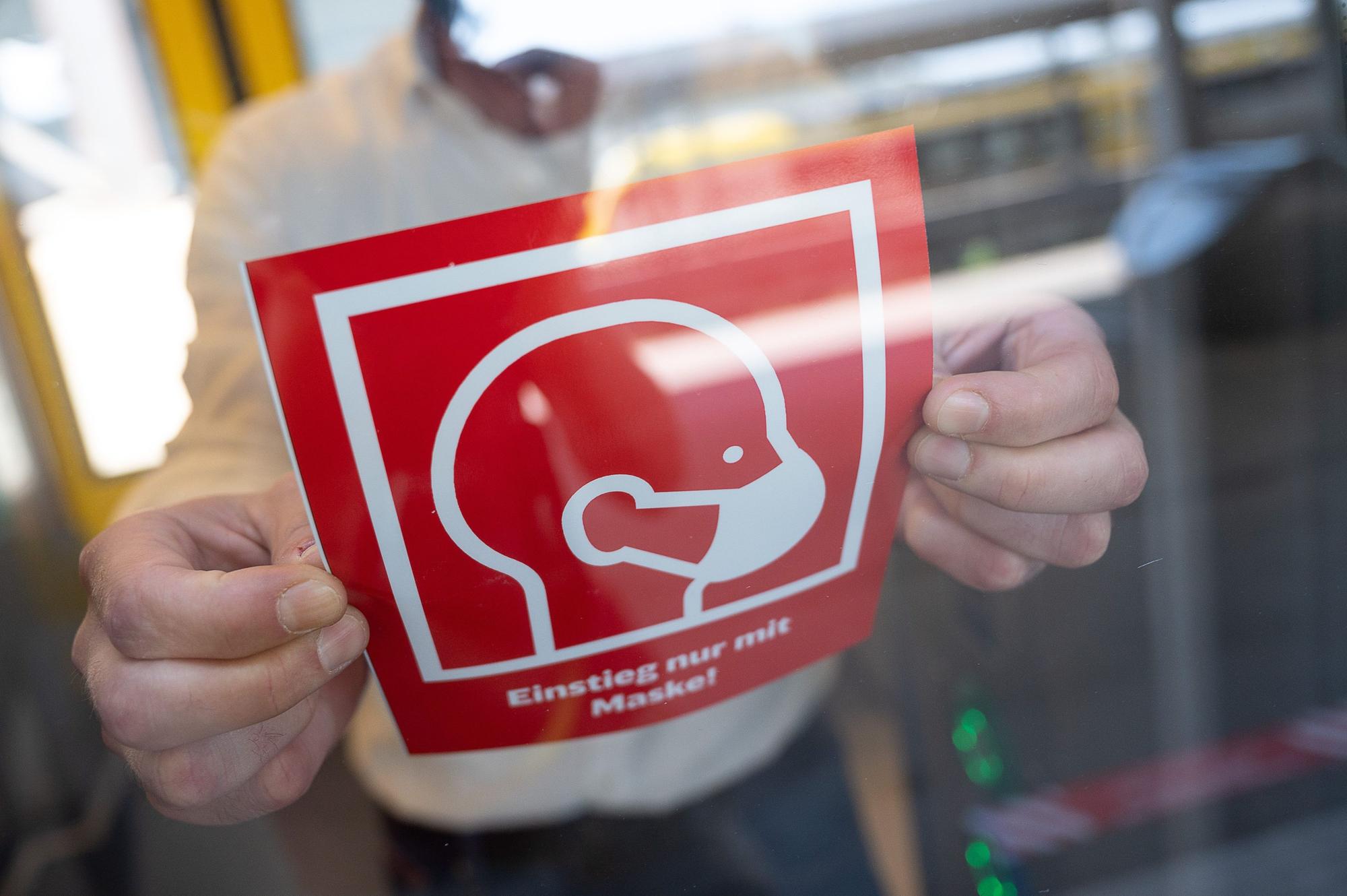 Ein Mitarbeiter der Bahn entfernt ein Schild zur Maskenpflicht.