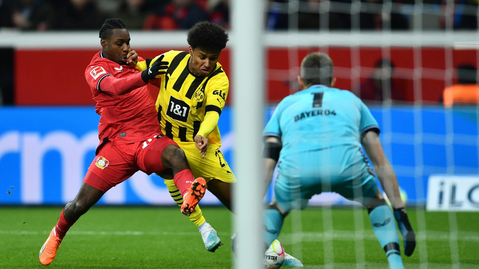 Dortmunds Karim Adeyemi (M) und Leverkusens Jeremie Frimpong kämpfen um den Ball.