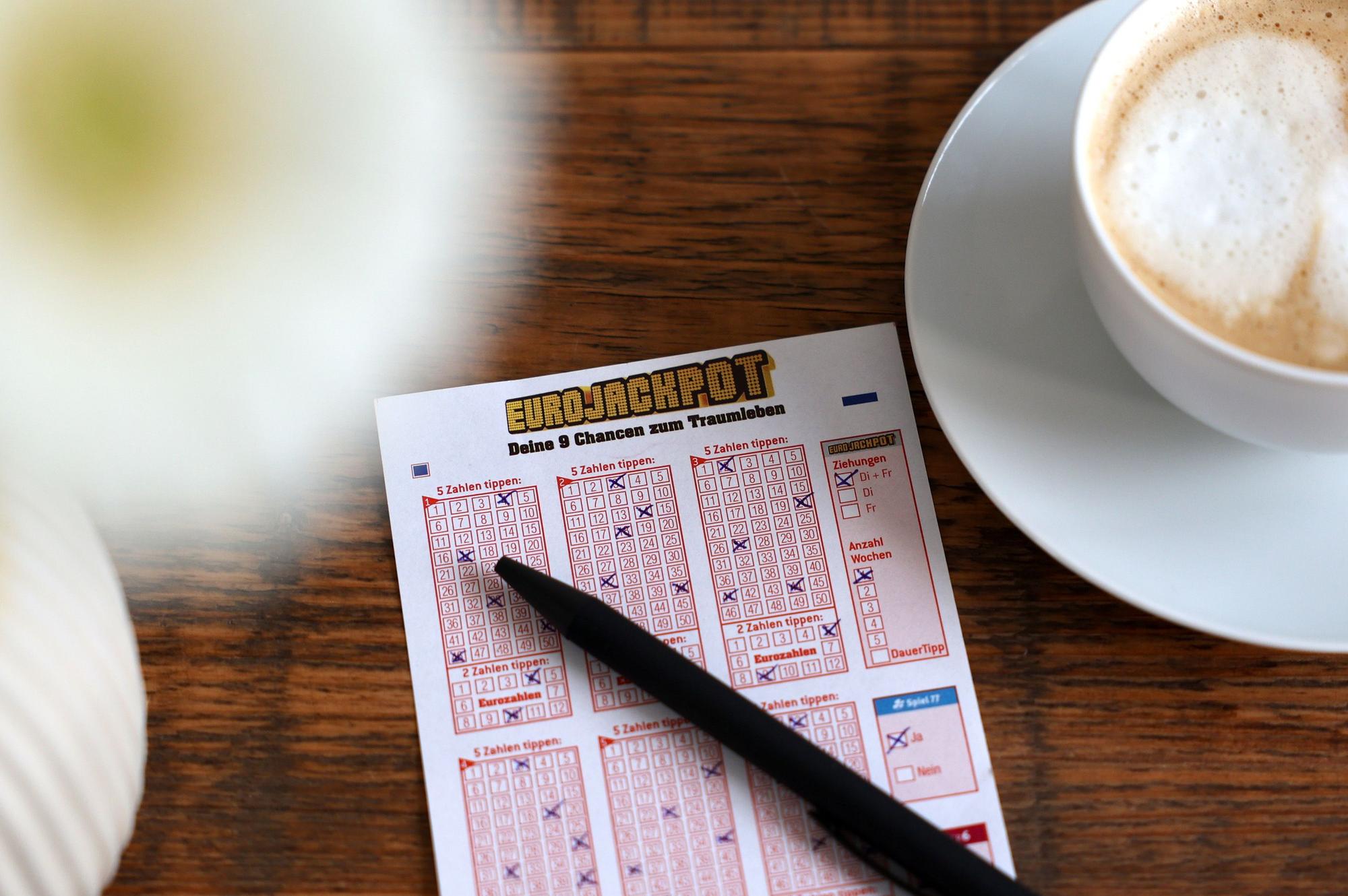Eurojackpot Spielschein liegt auf dem Tisch neben einer Tasse Kaffee.